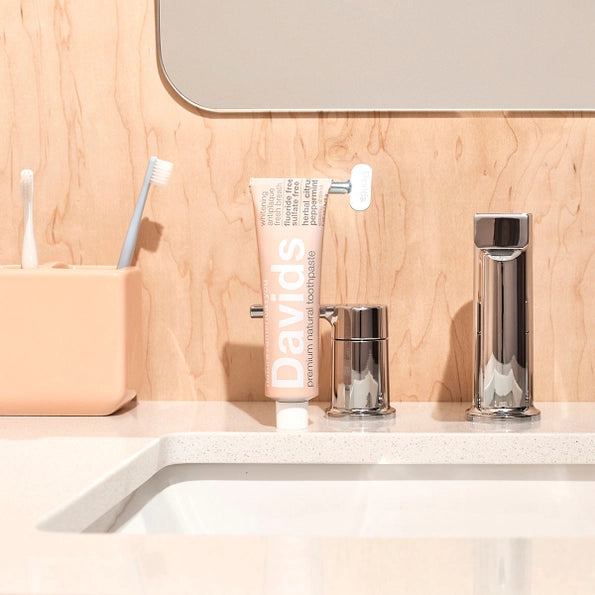 Bathroom counter with toothbrush, toothpaste, and bottles against a wooden wall.