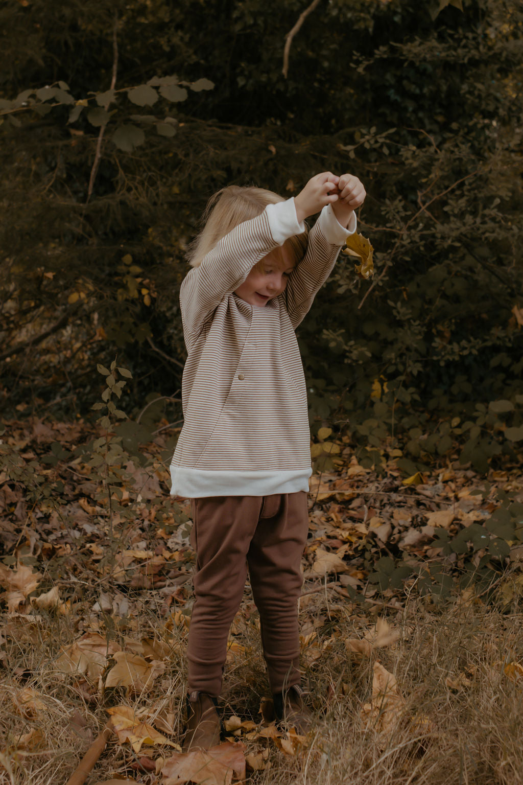 Child in a forest holding a leaf