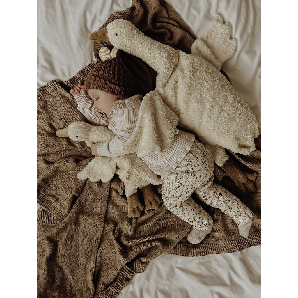 Child sleeping with stuffed animals and a blanket on a bed