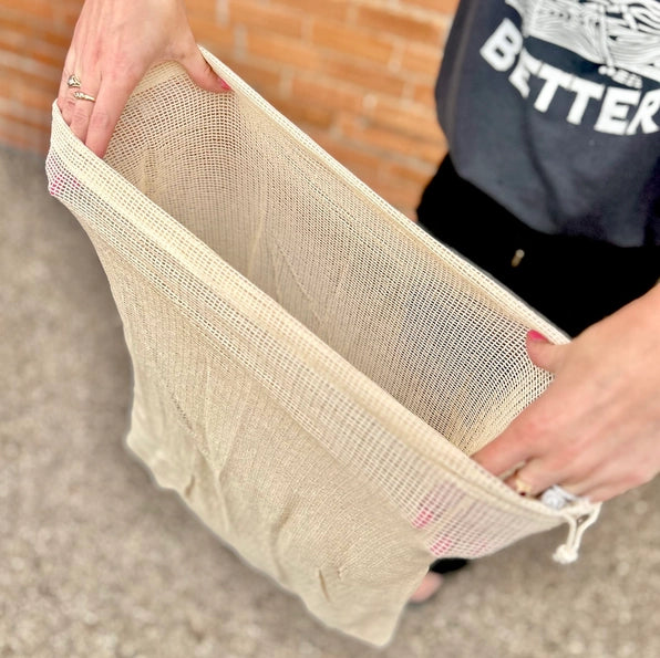 Person holding a beige mesh bag with a blurred background
