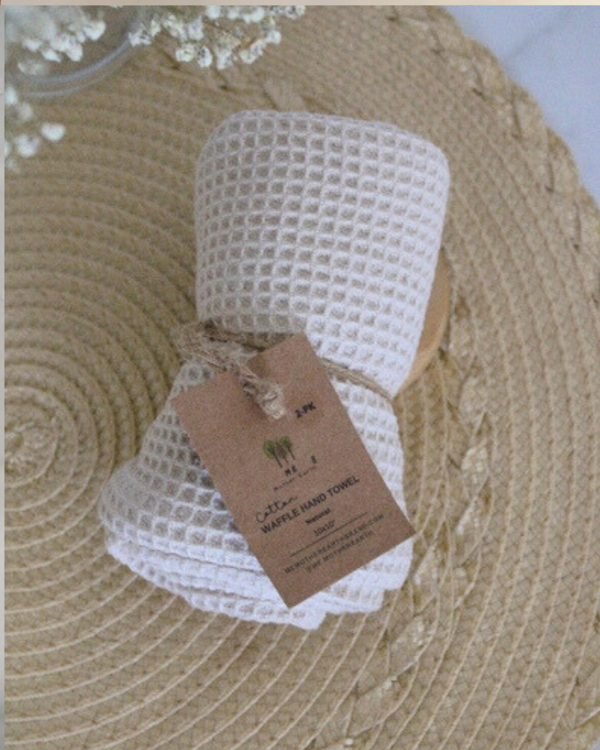 White woven hand towel with a brown tag on a textured surface