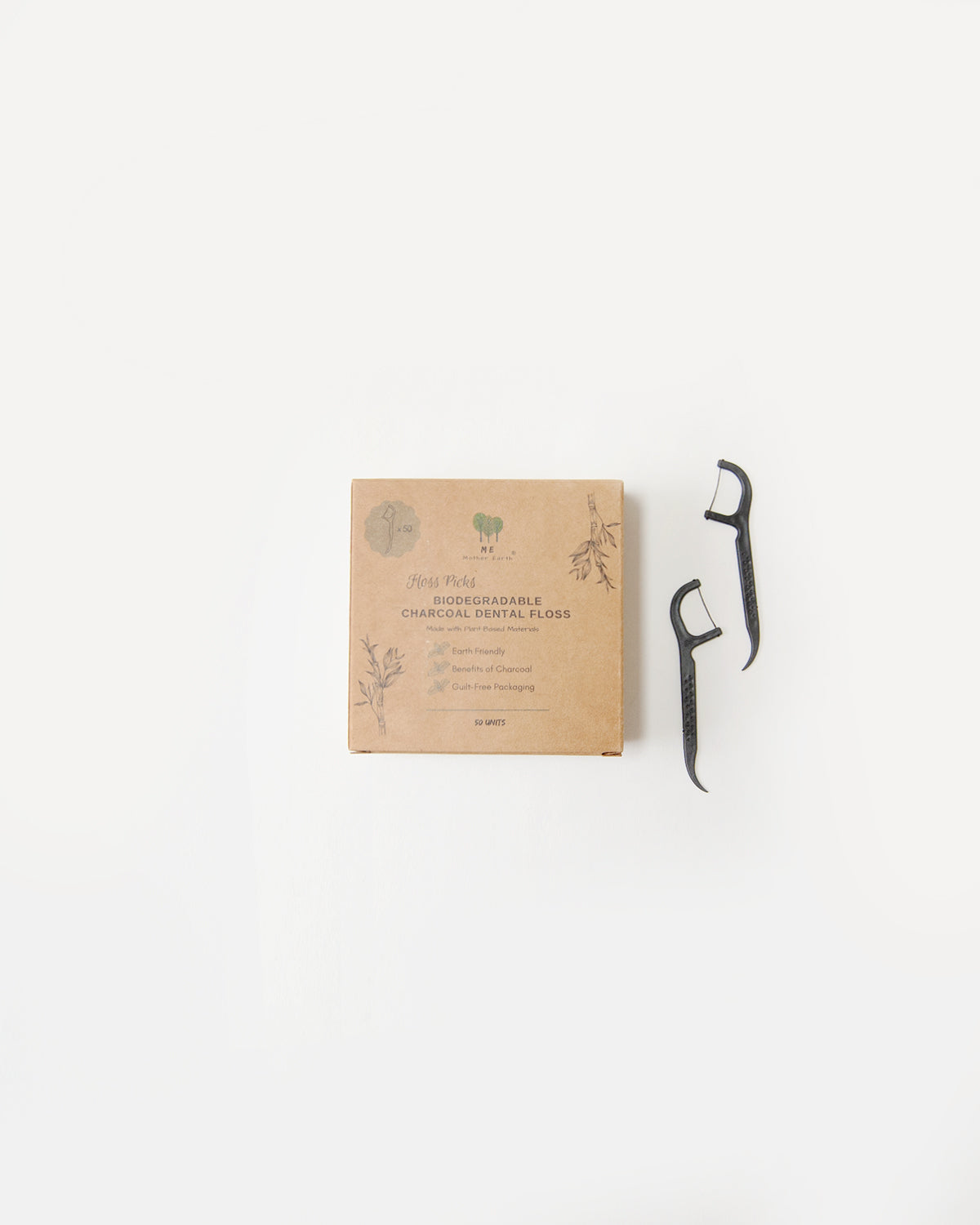 A kraft paper sleeve containing biodegradable charcoal dental floss picks, mounted on a wall.